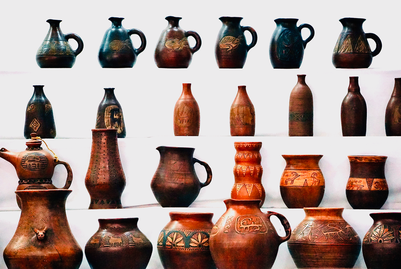 Collection of intricately designed pottery jugs and vases on a white background showcasing traditional craftsmanship.