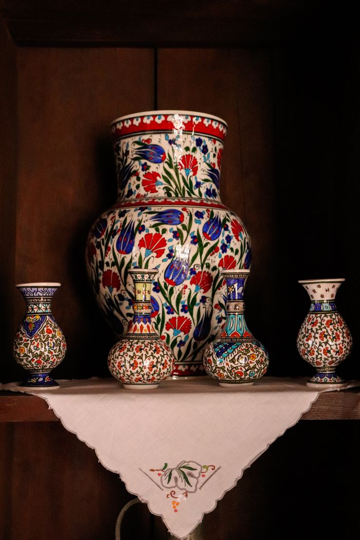 A vibrant display of floral-patterned ceramic vases on a wooden shelf.