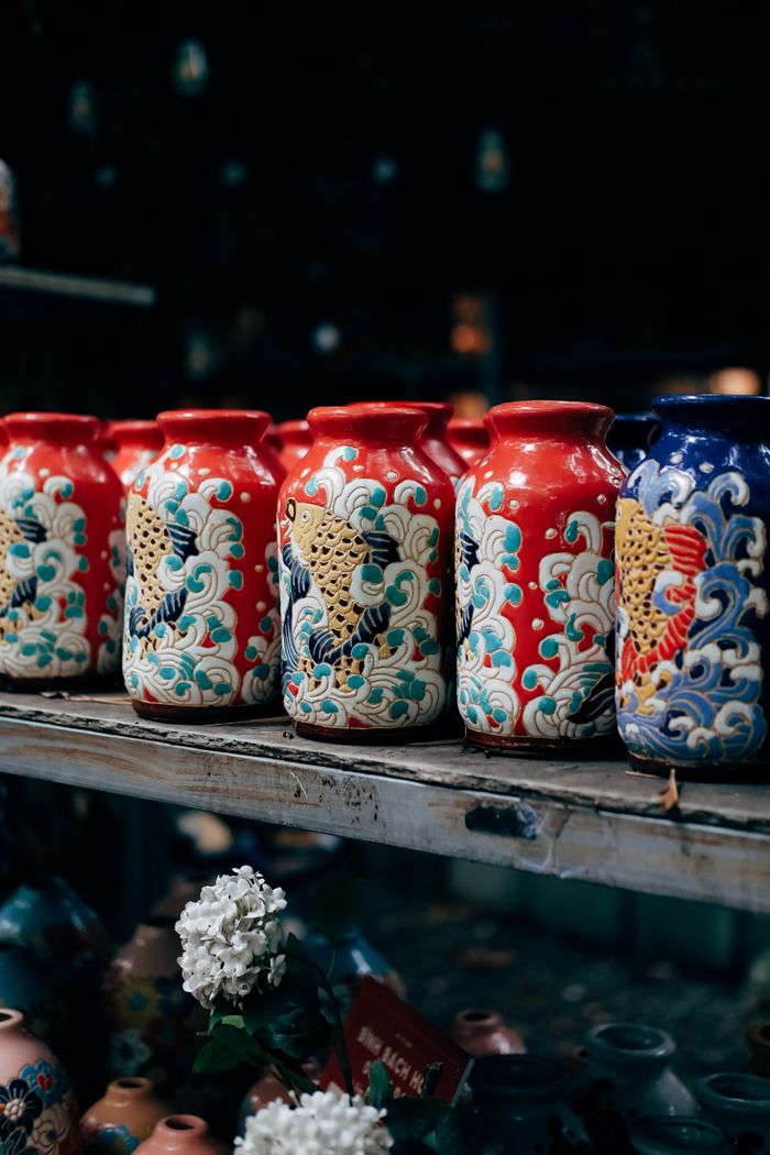 About Row of vibrant ceramic vases featuring intricate traditional Asian patterns on a wooden shelf.