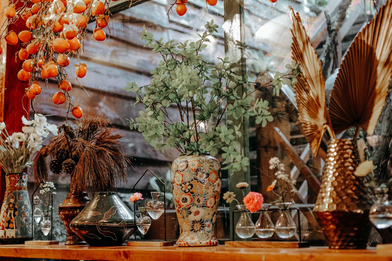 A vibrant still life featuring assorted vases and flowers in a warm setting.