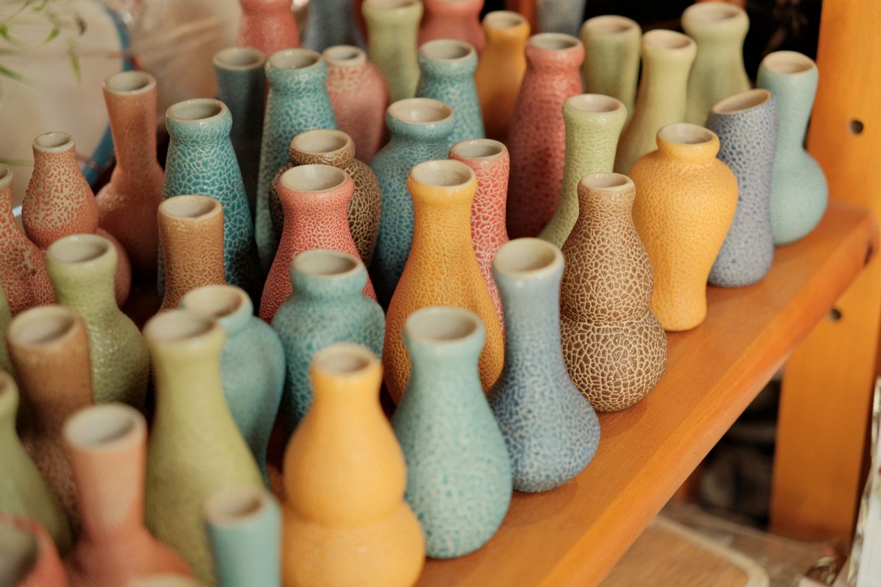 A collection of vibrant ceramic vases displayed on shelves in Hội An, Vietnam, showcasing artistic craft.