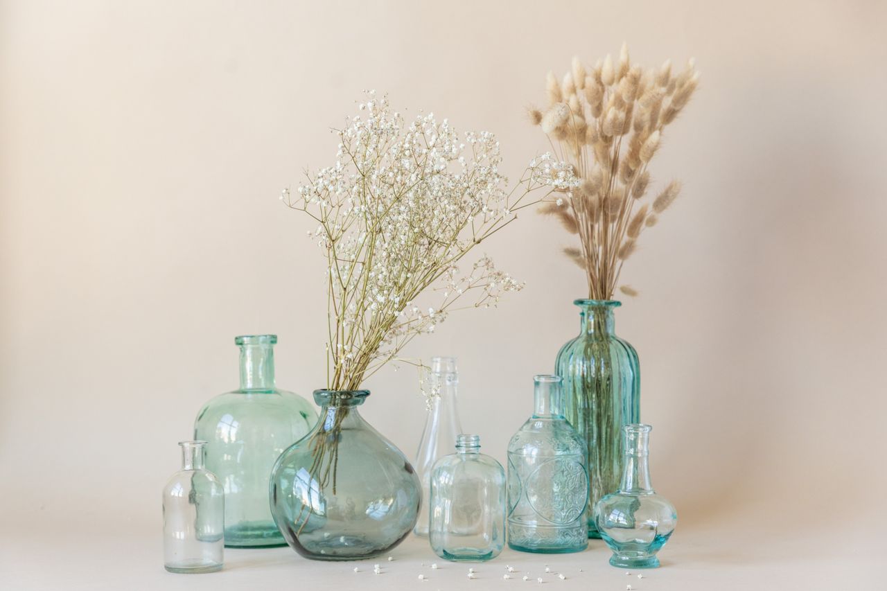 A collection of clear and blue recycled glass vases with decorative dried flowers, offering a minimalist and eco-friendly decor solution.